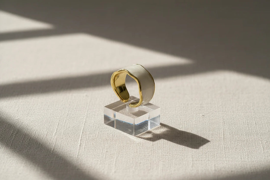 Pearl White Open Wave Ring displayed on a clear acrylic cube with dramatic window shadows, emphasizing the open adjustable band, smooth enamel finish, and gold-trim contour | OriaJewel