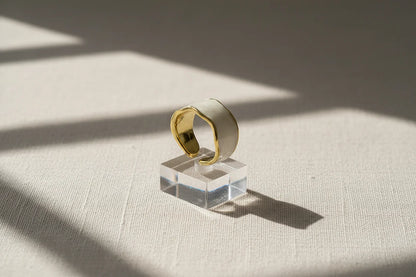 Pearl White Open Wave Ring displayed on a clear acrylic cube with dramatic window shadows, emphasizing the open adjustable band, smooth enamel finish, and gold-trim contour | OriaJewel
