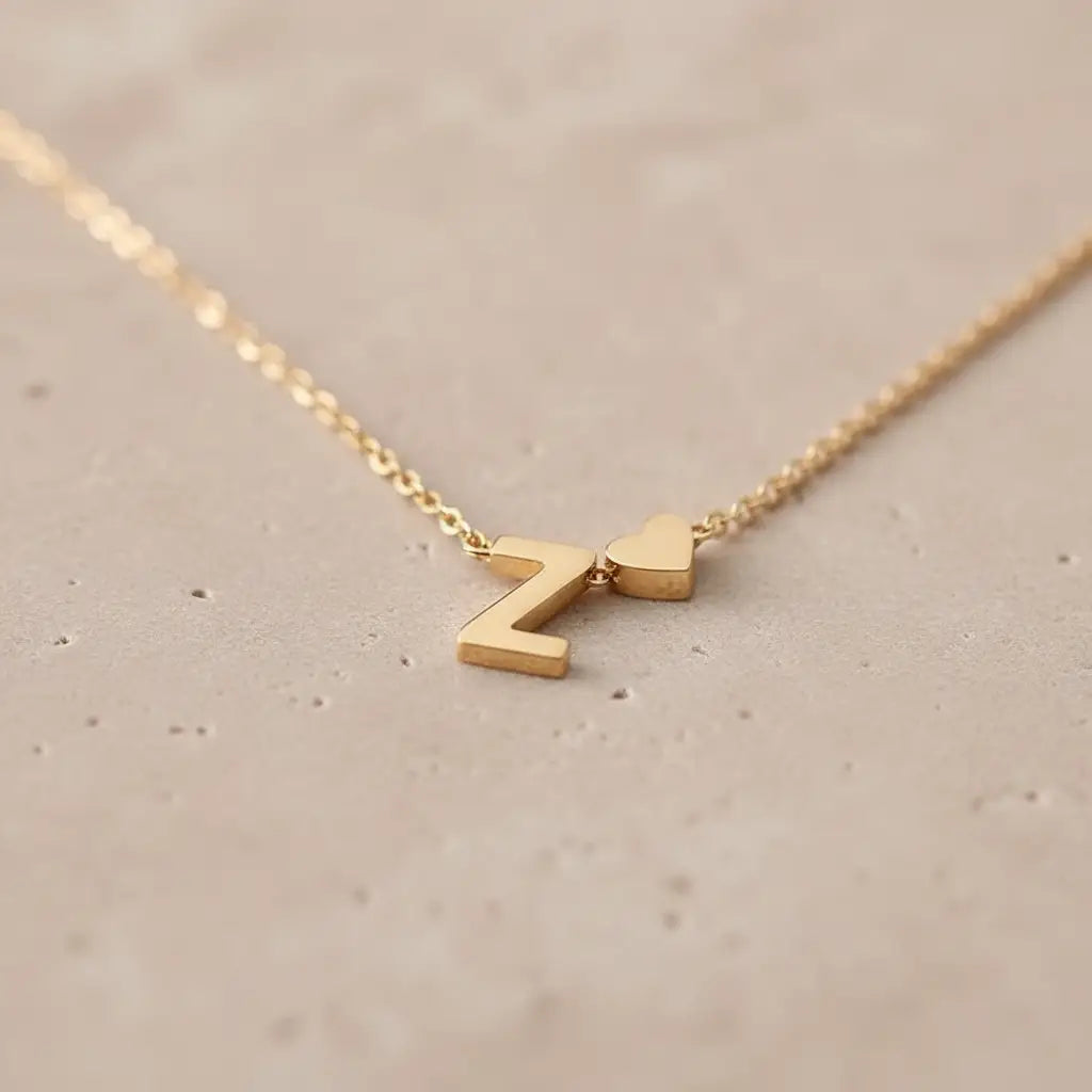 Macro shot of Personalised Heart Necklace Gold showing polished Z initial and heart charm resting on a textured stone surface | Oria Jewel