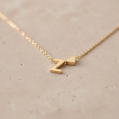 Macro shot of Personalised Heart Necklace Gold showing polished Z initial and heart charm resting on a textured stone surface | Oria Jewel