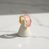 Pink Marble Open Wave Ring displayed on a small white cone stand over a marble surface, angled studio-style shot highlighting the open band and curved wave silhouette | OriaJewel