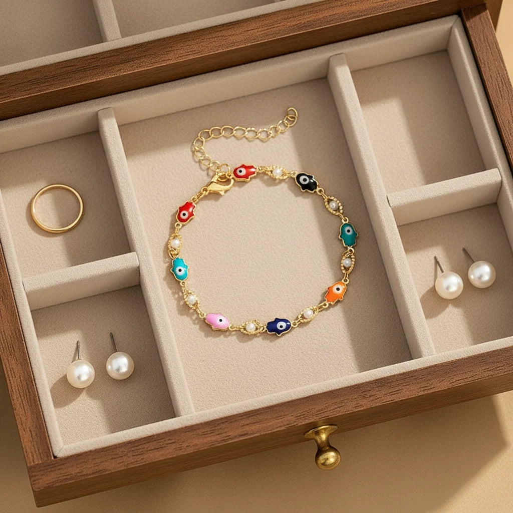 Jewelry drawer styled scene featuring the Rainbow Evil Eye Charm Bracelet neatly arranged beside pearl studs and a gold ring, highlighting its playful multicolor charms | Oria Jewel