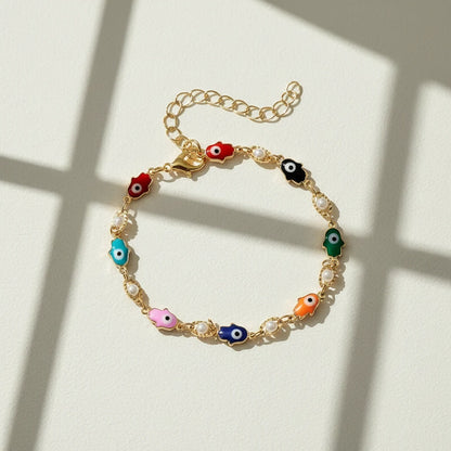 Minimal studio shot of the Rainbow Evil Eye Charm Bracelet on a light background, dramatic window shadows emphasizing the vivid enamel charms and dainty chain | Oria Jewel