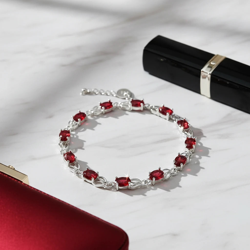 Glamorous scene of the Red Crystal Silver Tennis Bracelet laid on white marble next to a red clutch and black lipstick tube, the fiery red crystals and polished silver links catching the light for an evening look | Oria Jewel