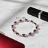Glamorous scene of the Red Crystal Silver Tennis Bracelet laid on white marble next to a red clutch and black lipstick tube, the fiery red crystals and polished silver links catching the light for an evening look | Oria Jewel