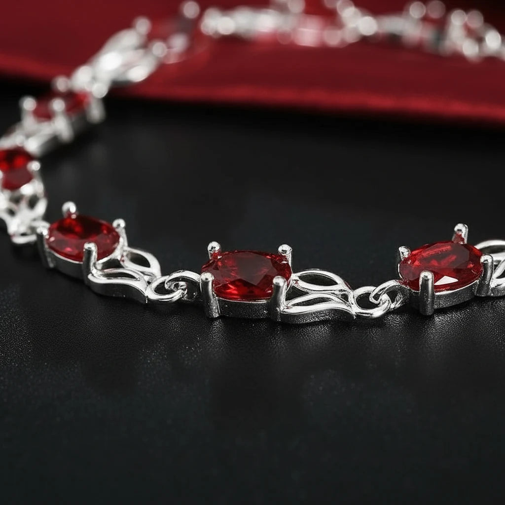 Macro shot of the Red Crystal Silver Tennis Bracelet on a black background, focusing on the faceted red crystals in claw settings and twisted silver links that create a luxurious tennis bracelet style | Oria Jewel