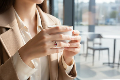 Hands holding a white coffee cup with a sparkling heart halo ring, Red Heart Halo CZ Ring | OriaJewel