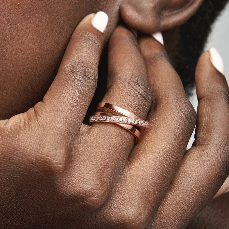Rose Gold Criss Cross CZ Band Ring worn on a finger in a lifestyle close-up, highlighting the polished rose gold crossover bands and the thin center strip of pavé CZ stones | OriaJewel