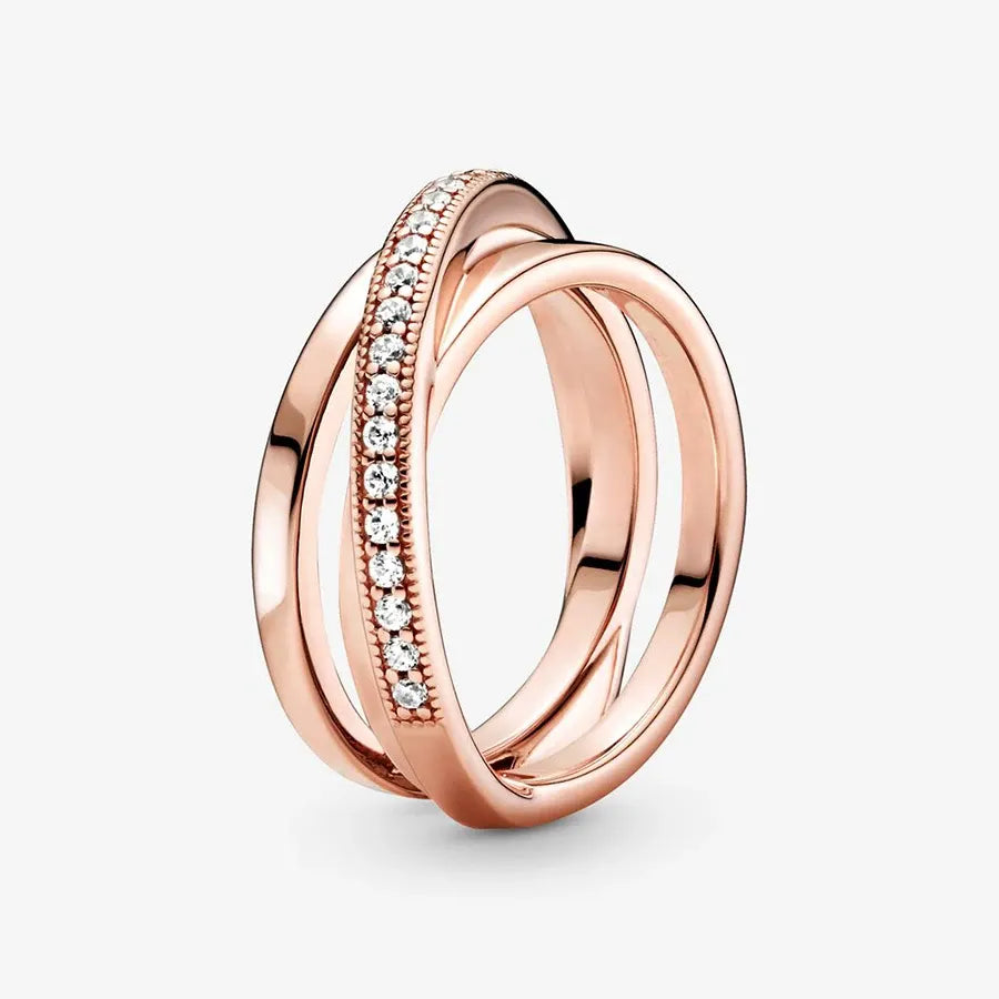 Rose Gold Criss Cross CZ Band Ring isolated on a white background in an angled view, emphasizing the intertwined rose gold bands and the CZ-set band with bead-detailed edges | OriaJewel