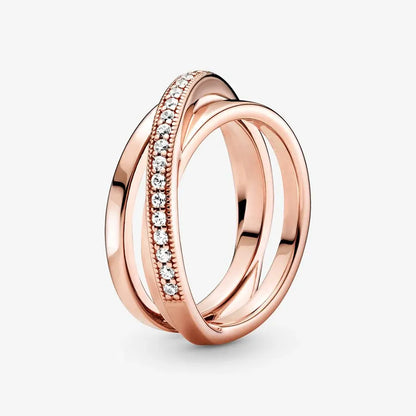 Rose Gold Criss Cross CZ Band Ring isolated on a white background in an angled view, emphasizing the intertwined rose gold bands and the CZ-set band with bead-detailed edges | OriaJewel