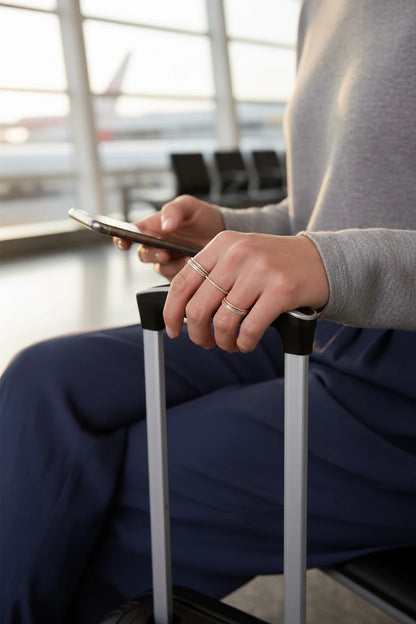 Rose Midi Ring Set stacked midi rings on hand holding a phone at an airport lounge, suitcase handle in foreground | OriaJewel
