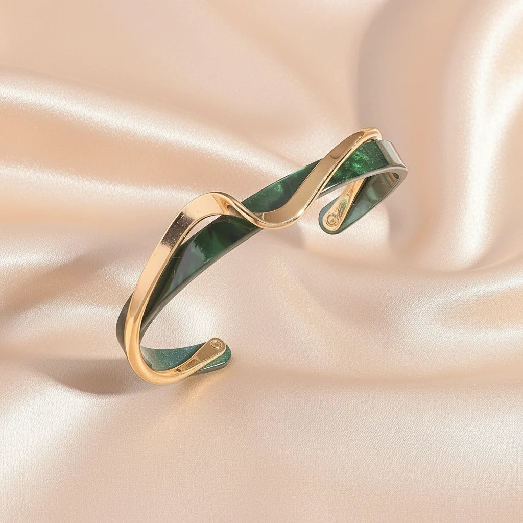 Close-up of the green marbled and gold Rosette twist cuff bracelet resting on soft champagne satin fabric, highlighting its sculpted wavy design and glossy finish | Oria Jewel
