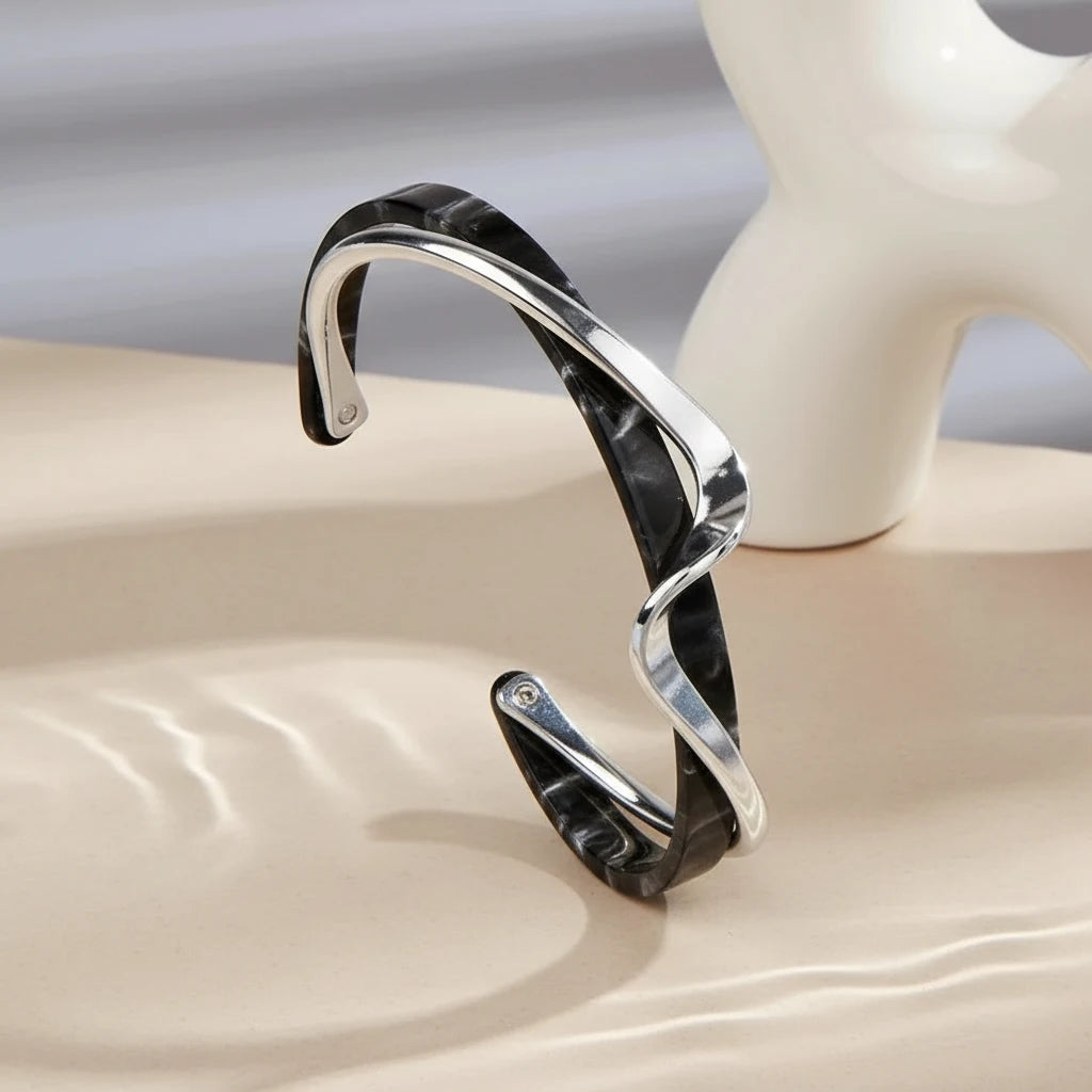 Black marbled Rosette twist cuff bracelet with sleek silver twist detail standing upright on a neutral surface beside a sculptural white vase | Oria Jewel