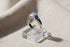 Royal Blue Princess Cut Ring close-up on a clear acrylic block over soft beige fabric, detailed side profile showing the square center stone and rich blue triangular side stones | OriaJewel