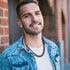Man wearing a chunky stainless steel Bold Cuban Chain Necklace against a brick wall, showcasing a stylish look.