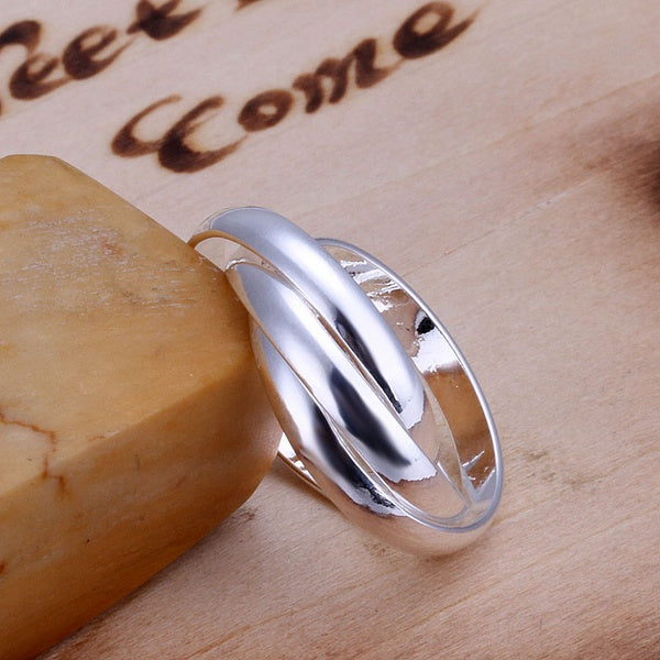 Sterling silver wedding ring by OriaJewel featuring an elegant twisted design on a wooden background.