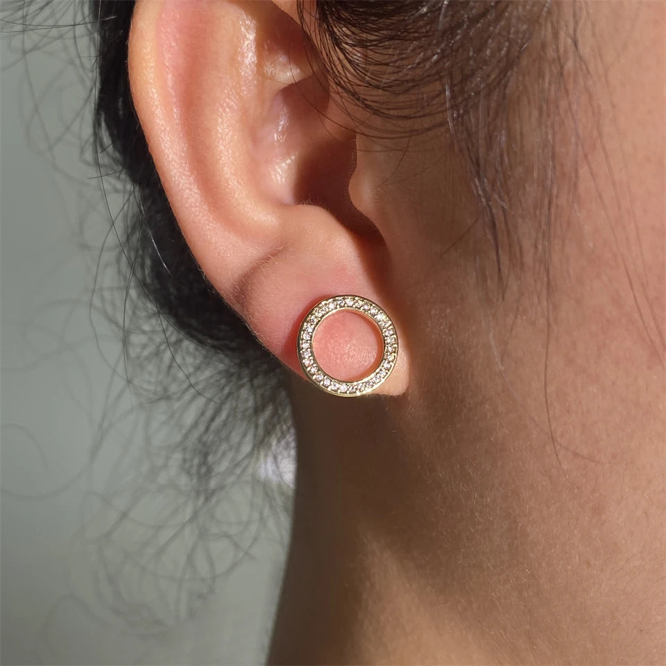 Hollow Zircon Earrings: a gold circular stud glistening on an earlobe | Oria Jewel