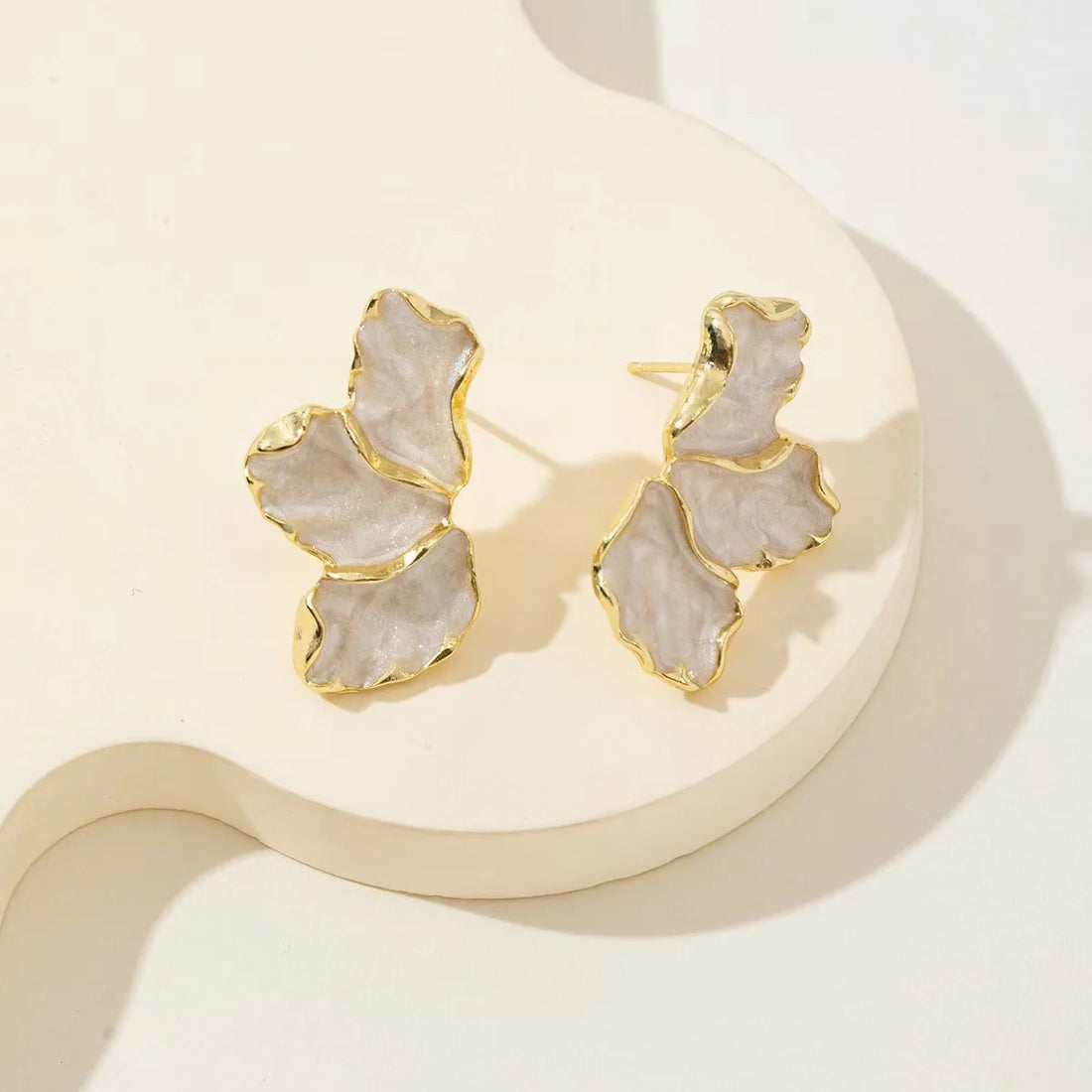 Two irregular creamy daisy hoops, gold-edged, displayed on a light stand | Oria Jewel