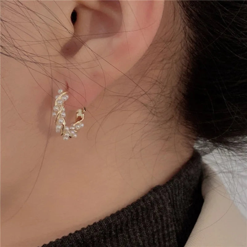 Intricate gold freshwater pearl hoop earrings worn on an ear, close-up | Oria Jewel