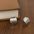 Two ribbed, chunky gold earrings on dark wood with a book | Oria Jewel