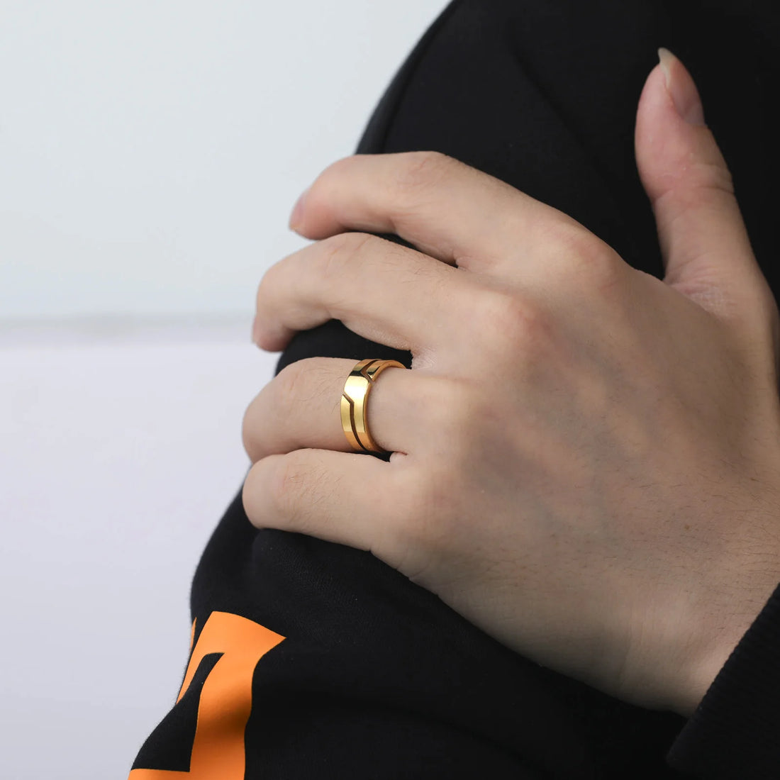 Close-up: a polished Geometric Gold Band Ring on a hand over dark fabric | Oria Jewel