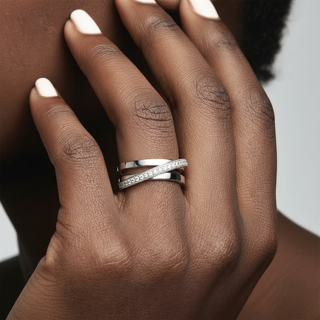 Close-up of a hand wearing a Crossover Band Ring with diamonds on a smooth, elegant background | Oria Jewel