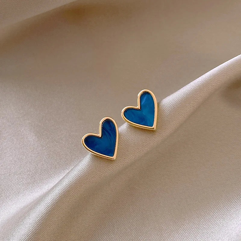 Softly lit gold and blue Mini Vintage Heart Studs on champagne satin | Oria Jewel