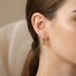 Elegant Small Hoop Star Earrings in shiny gold, beautifully worn by a woman model | Oria Jewel
