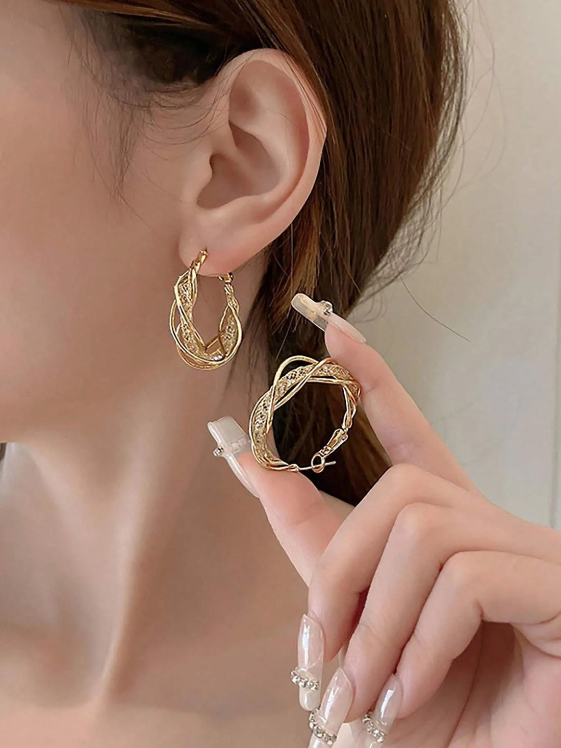 Close-up of woman modeling braided gold hoop daisy earrings, bright light | Oria Jewel