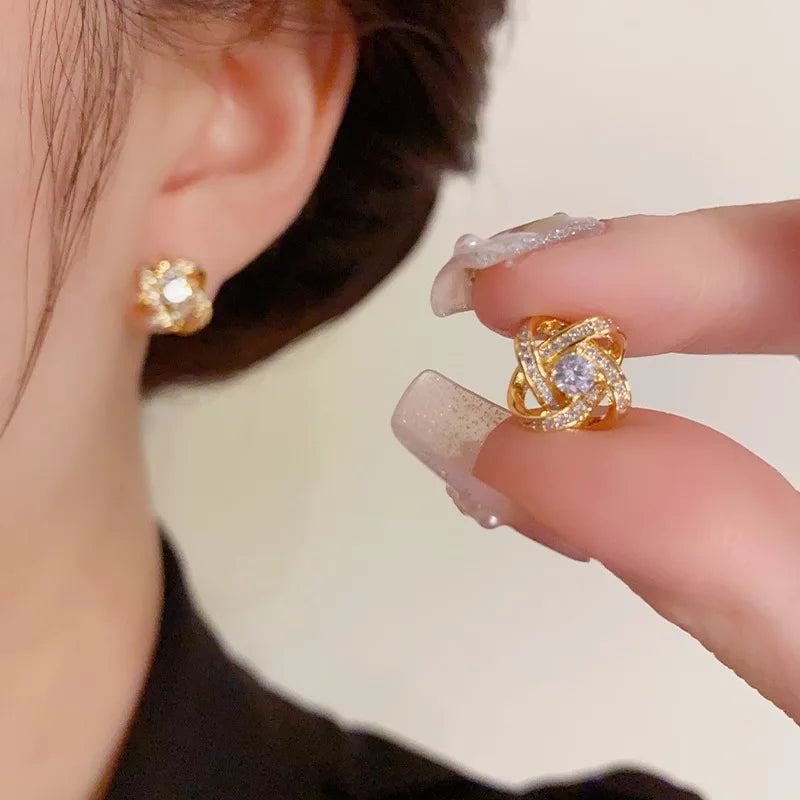 Sparkling gold Crystal Knot Earrings, one worn, one held by fingers | Oria Jewel