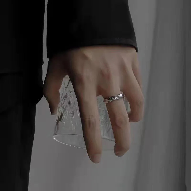 Close-up: hand holds textured glass, featuring a Twisted Silver Band Ring | Oria Jewel