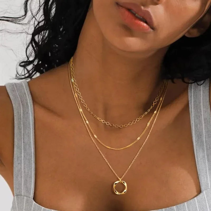 Model wearing multi layered gold chain necklace with minimal outfit and warm glow | Oria Jewel