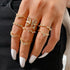 Hand with white nails displays ornate, sparkling gold Butterfly & Pearl Stacking Ring Set | Oria Jewel