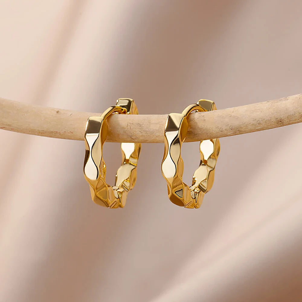 Two Wavy Gold Mini Hoops dangle from a wooden dowel against a soft background | Oria Jewel