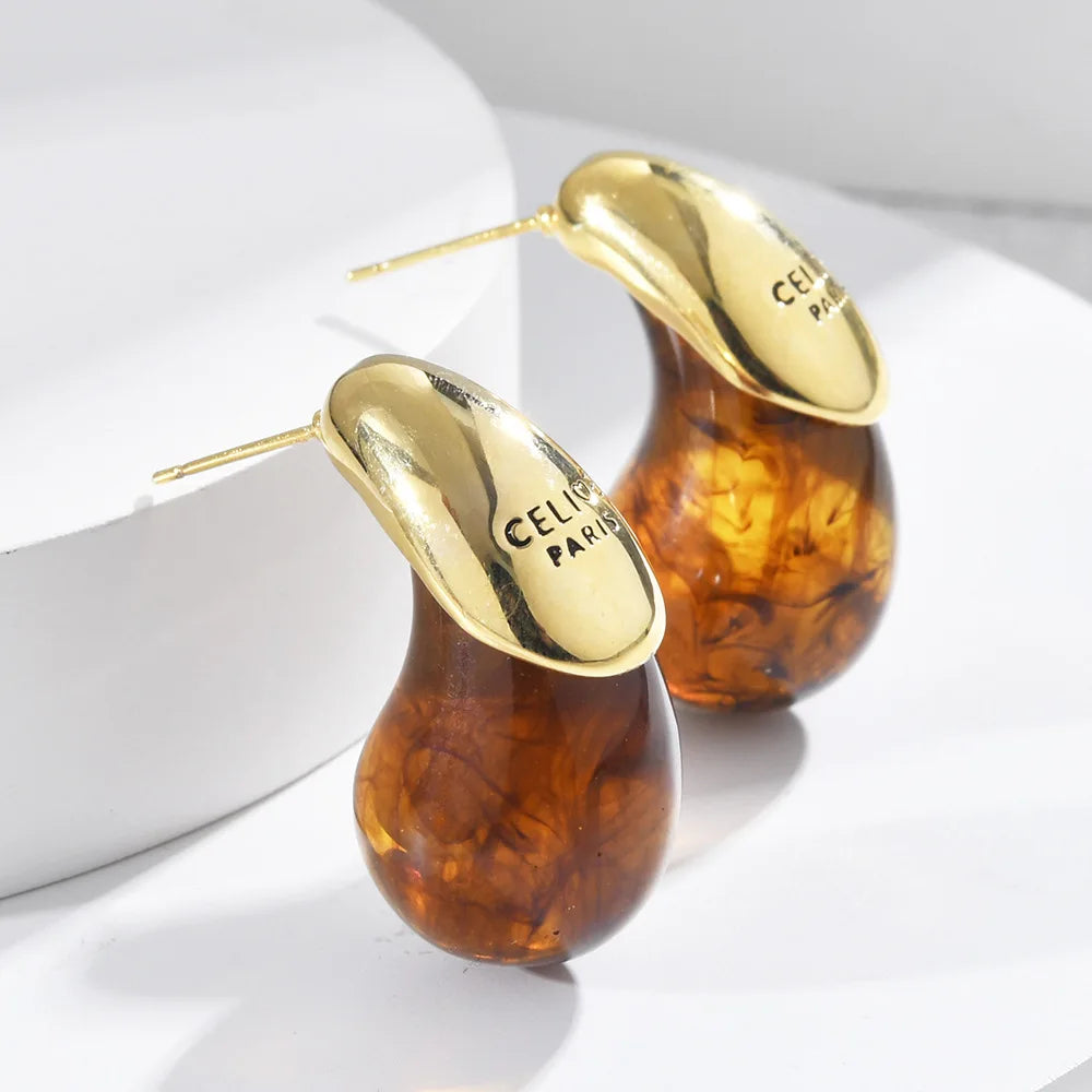 Golden-capped amber Water Drop Resin Earrings brightly lit on a white surface | Oria Jewel