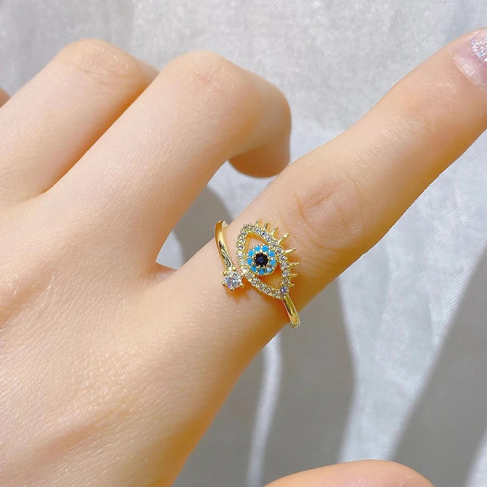 Blue Crystal Evil Rings with an eye design, featuring colorful crystals and gold accents, worn on a finger | Oria Jewel