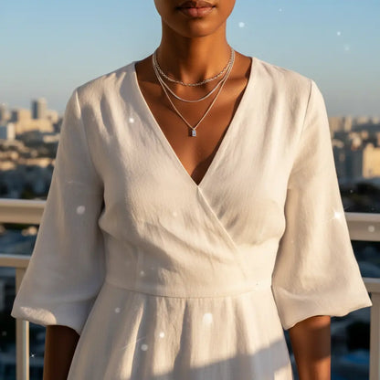 Silver A Initial Layered Necklace styled with white wrap dress on balcony overlooking city at golden hour | Oria Jewel