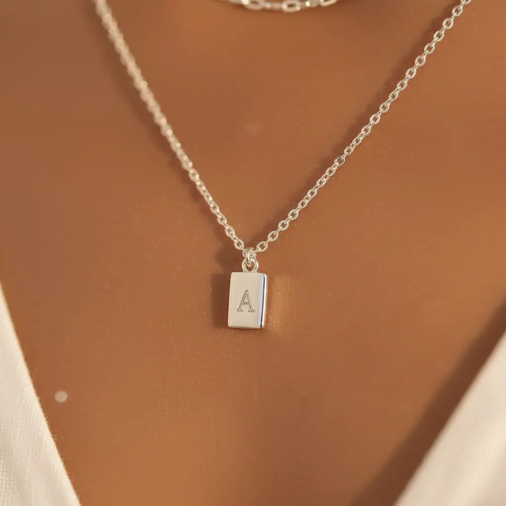 Close-up of dainty pendant on Silver A Initial Layered Necklace showing engraved letter A on rectangular charm | Oria Jewel