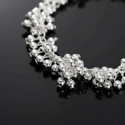 Close-up macro shot of the Silver Beaded Cluster Bracelet on a glossy black surface, emphasizing the reflective shine of the tightly packed silver beads and intricate clustered design | Oria Jewel