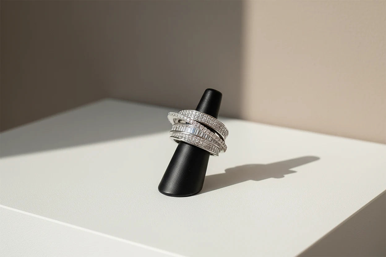 Silver CZ Wrap Ring displayed on a black ring stand under soft daylight, showing the layered wrap bands with pavé CZ sparkle and baguette row detail | OriaJewel