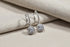 Silver Crystal Drop Huggie Earrings on beige fabric with soft folds | OriaJewel