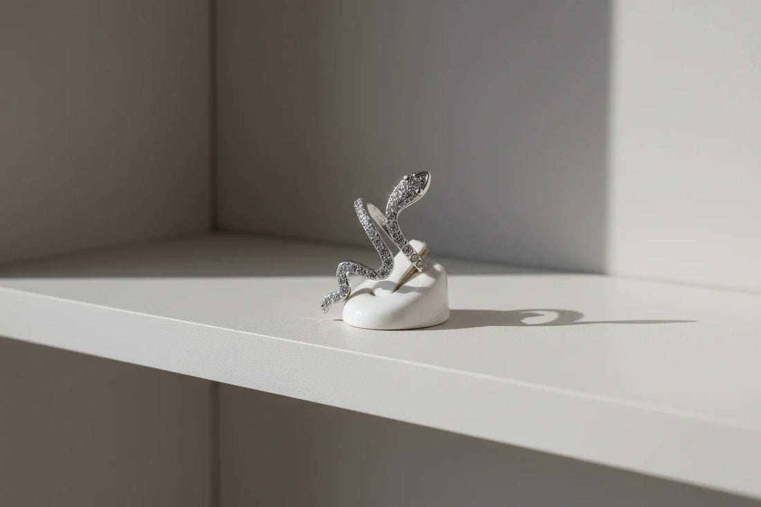 Silver Pavé Snake Wrap Ring displayed on a small white ring holder on a clean shelf, side-angle studio scene emphasizing the open wrap design and shimmering pavé finish | OriaJewel