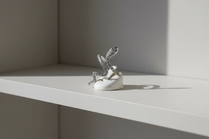 Silver Pavé Snake Wrap Ring displayed on a small white ring holder on a clean shelf, side-angle studio scene emphasizing the open wrap design and shimmering pavé finish | OriaJewel