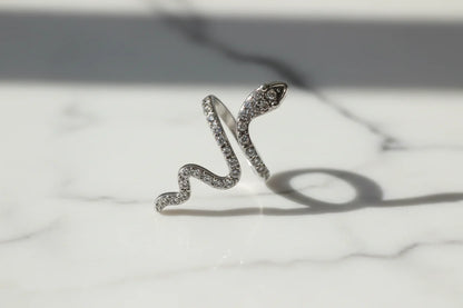 Silver Pavé Snake Wrap Ring macro on a white marble surface with soft natural reflections, detailed view of the pavé-set snake head and winding band | OriaJewel
