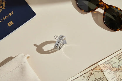 Travel flat lay featuring Silver Safety Pin Ring on a beige surface beside a navy passport, sunglasses, a jewelry pouch, and a vintage map for a chic getaway vibe | OriaJewel