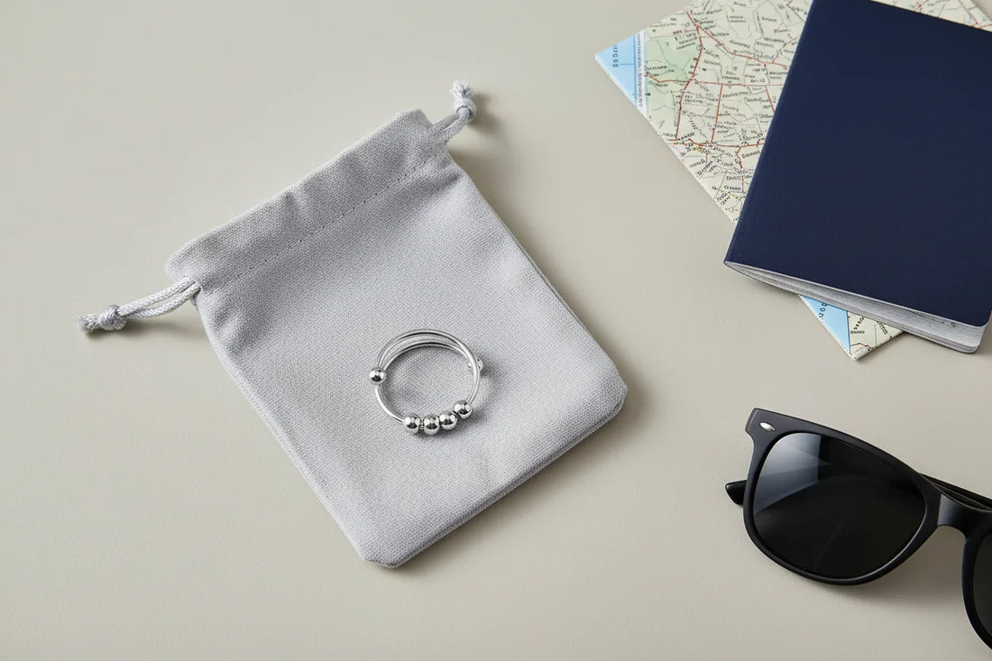Travel-inspired flat lay featuring the Silver beaded stackable ring placed on a soft gray pouch, with a passport, map, and black sunglasses on a neutral surface under gentle natural light | OriaJewel