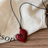 Simple Heart Pendant Necklace displayed on a fabric surface with a black cord and a red heart-shaped pendant | Oria Jewel
