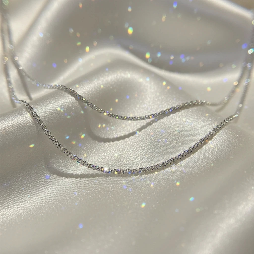 Sparkling Chain Necklace in silver displayed on soft satin fabric with glitter reflections | Oria Jewel