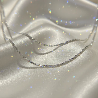 Sparkling Chain Necklace in silver displayed on soft satin fabric with glitter reflections | Oria Jewel