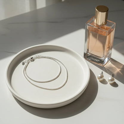 Sparkling Chain Necklace arranged on ceramic plate beside perfume bottle and pearl earrings | Oria Jewel